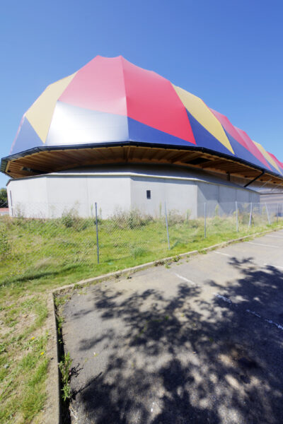 Le Plongeoir - Cité du Cirque au Mans : vue arrière du chapiteau permanent, coiffé de sa toile de couleurs rouge, bleu et jaune 